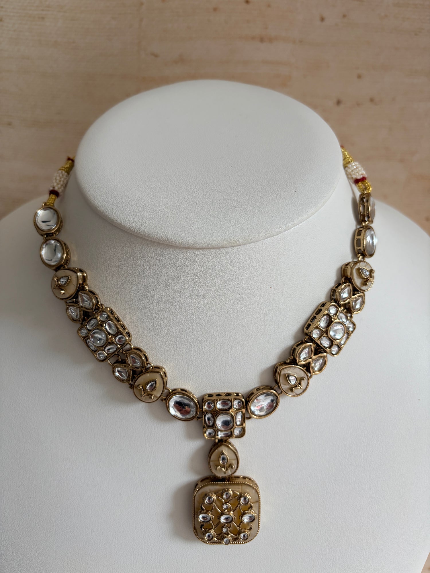 Decorative necklace on a white mannequin bust against a wooden background