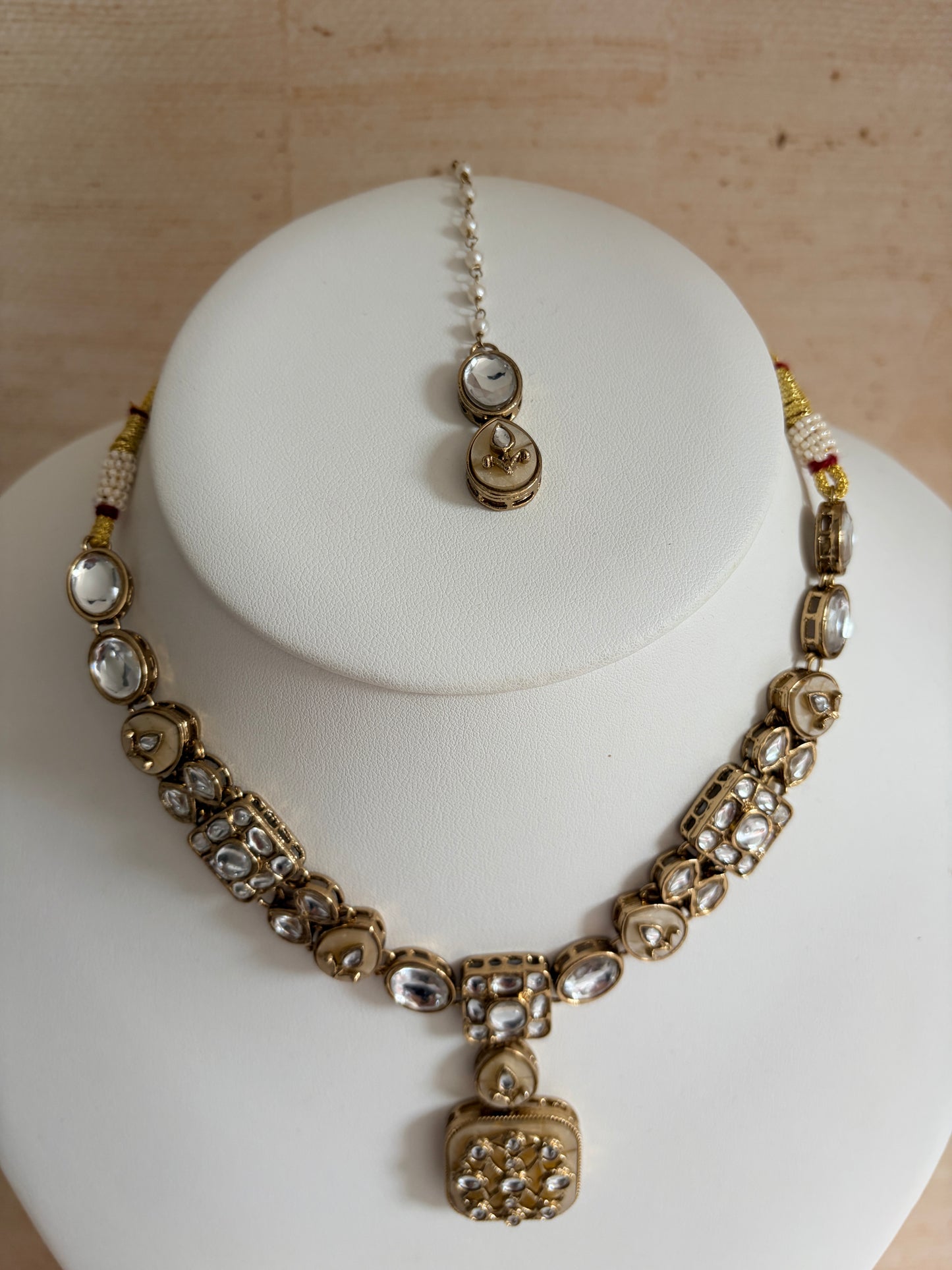 Gold and silver bracelet on a white stand with a wooden background