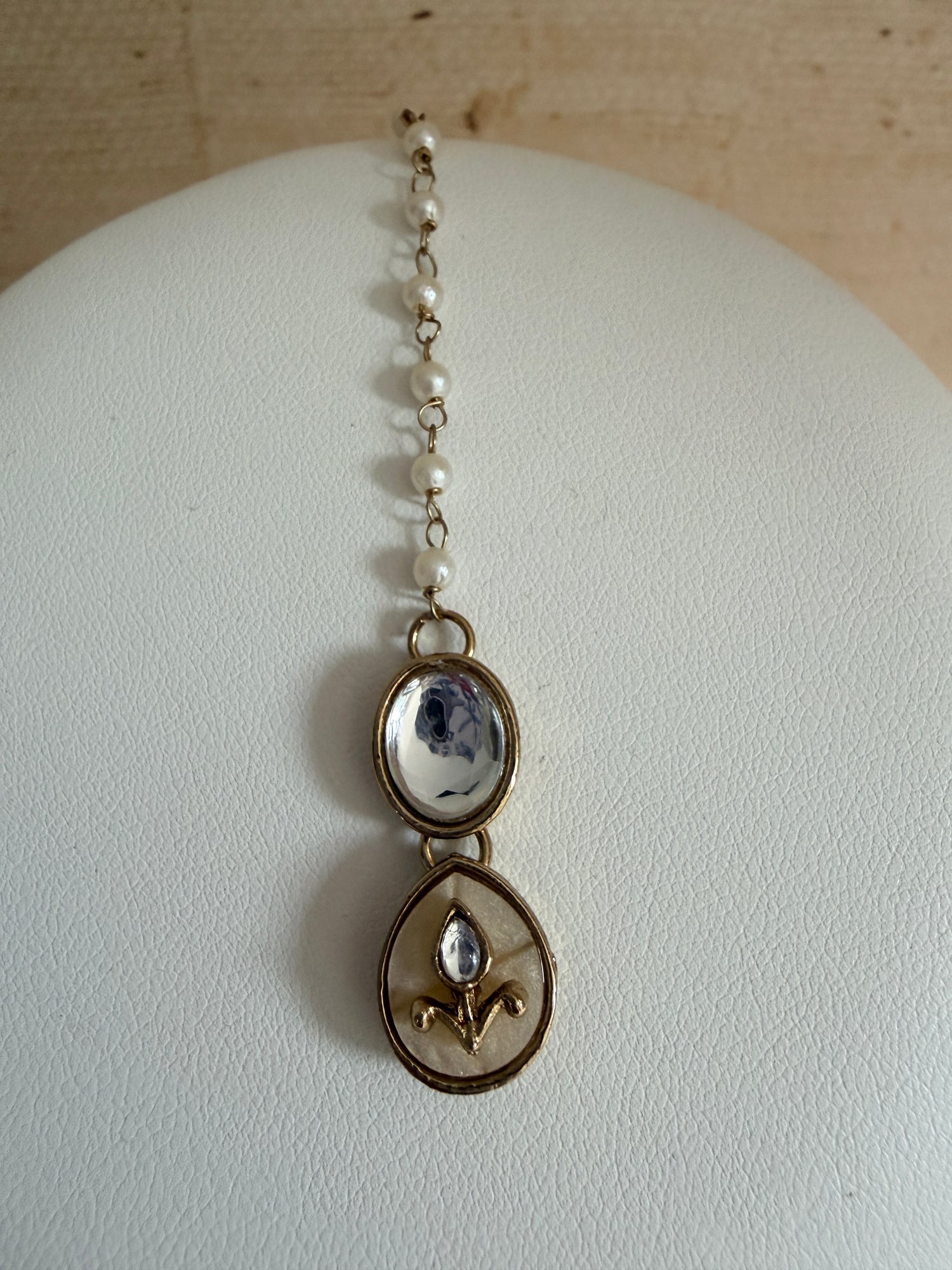 Delicate bracelet with gemstones on a mannequin head against a neutral background