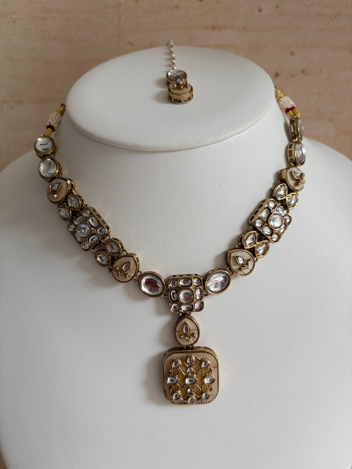 Gold bracelet with clear stones on a white mannequin bust.