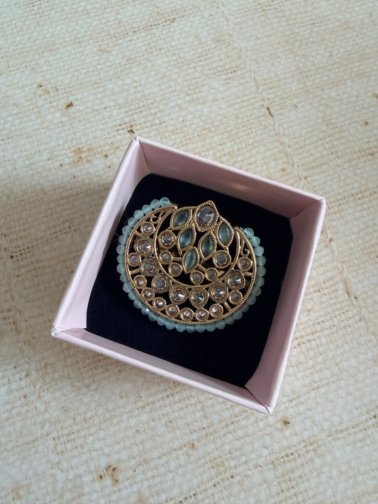 Decorative brooch in a pink box on a textured beige surface