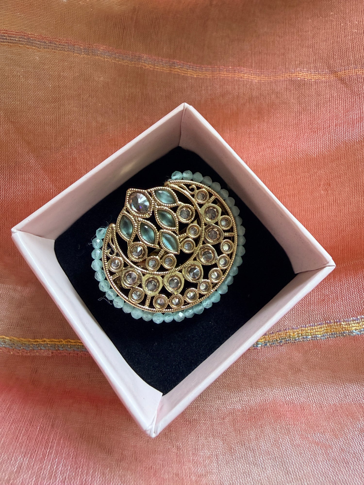 Decorative brooch in a white box on a fabric background