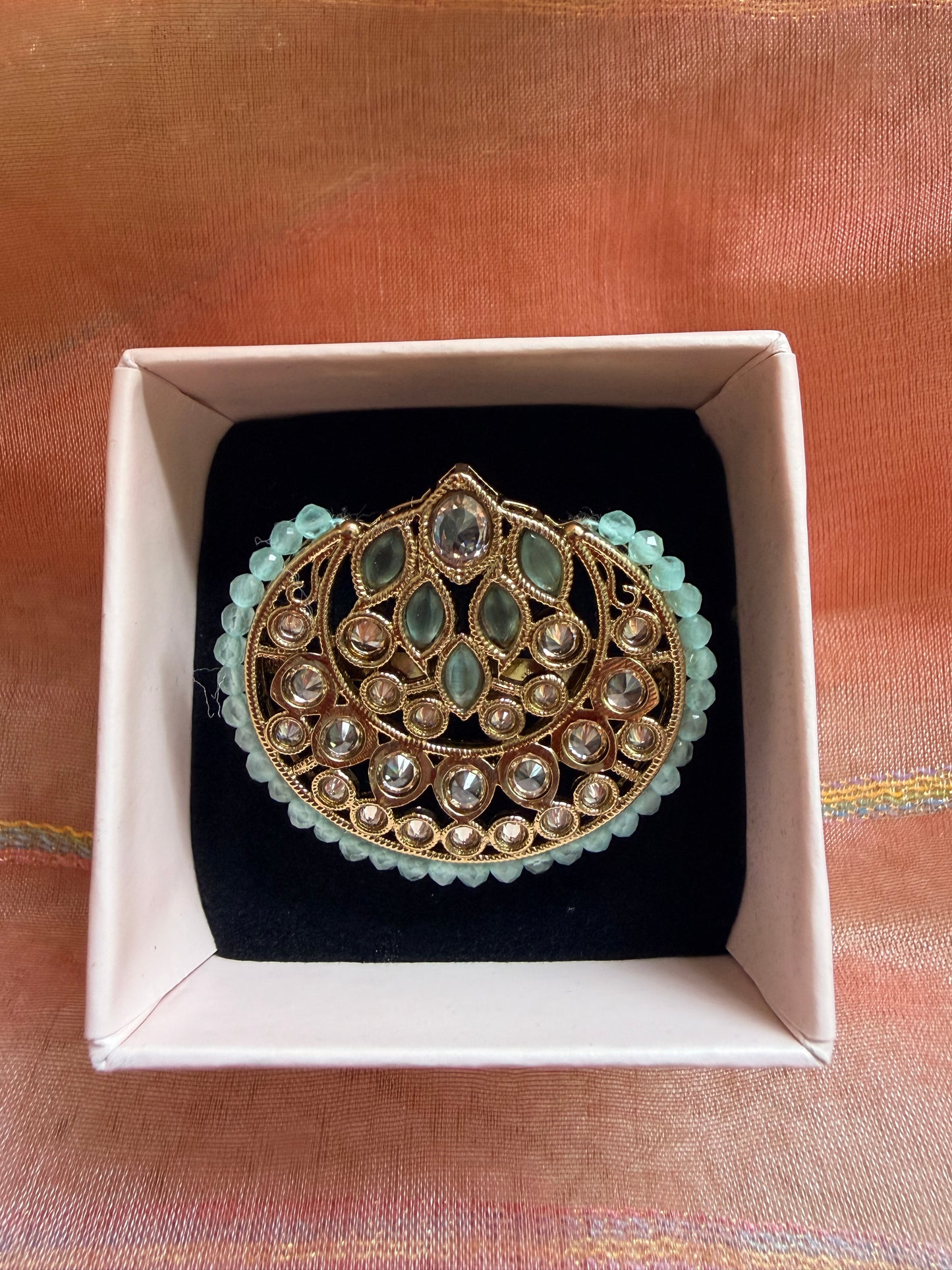 Decorative brooch in a box on a textured fabric background