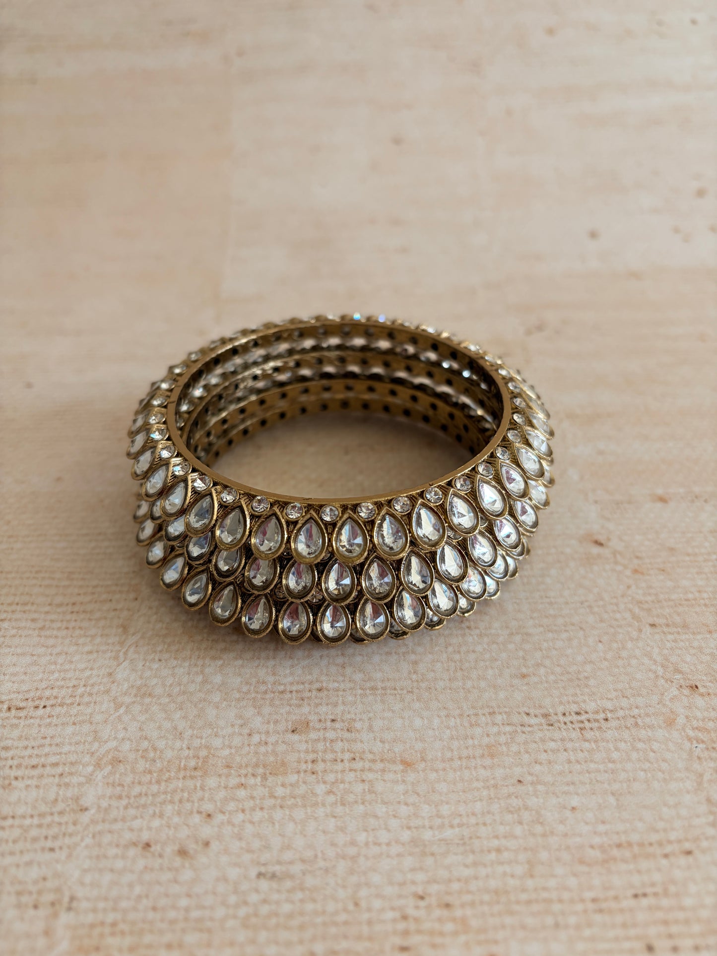 Stack of gold and crystal rings on a beige fabric background