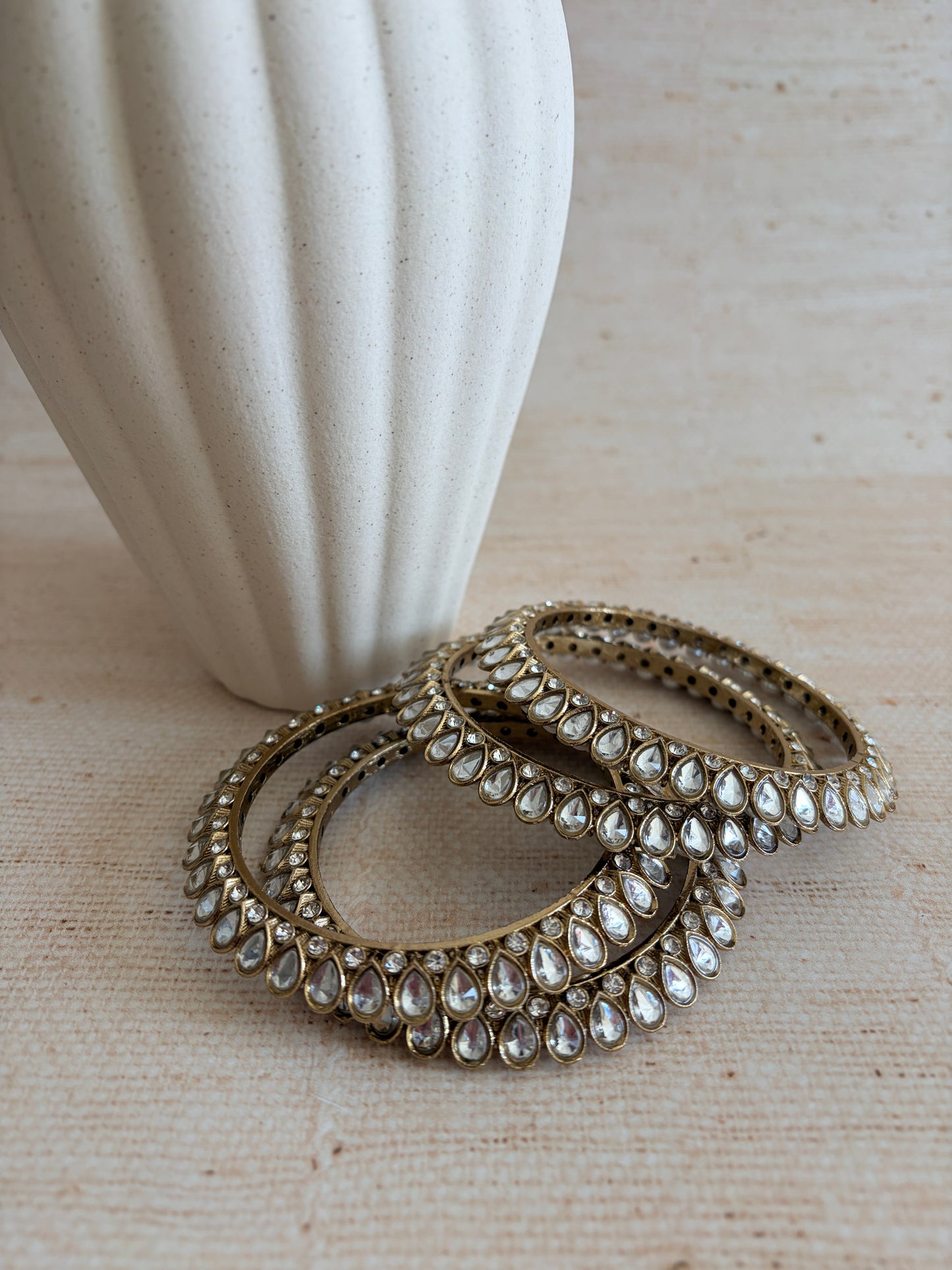 Decorative ring with gemstones on a white pedestal against a beige background