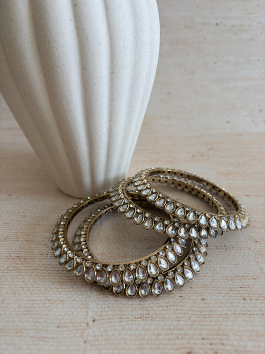 Decorative ring with gemstones on a white pedestal against a beige background