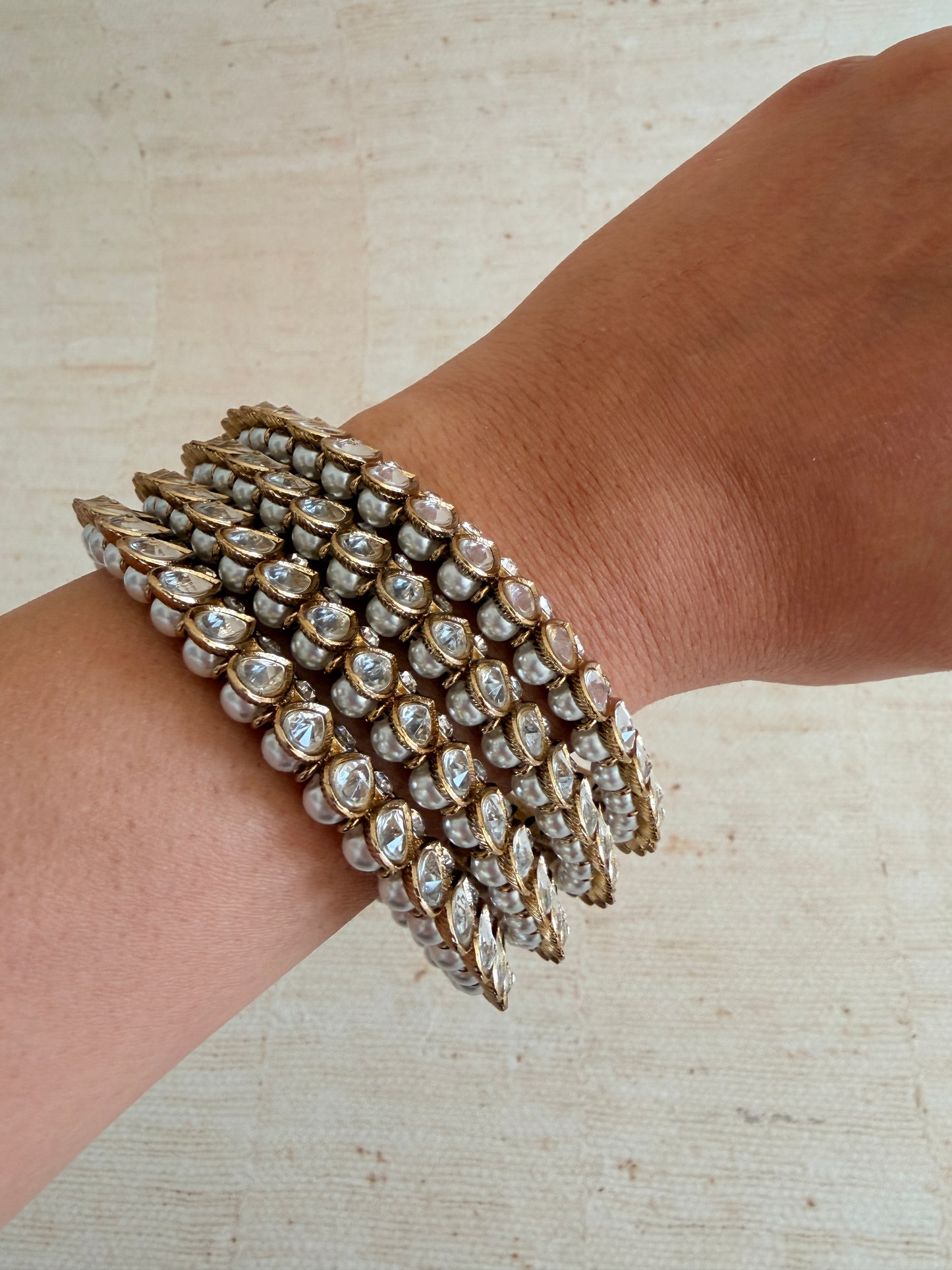 Stack of ornate bracelets on a wrist against a neutral background