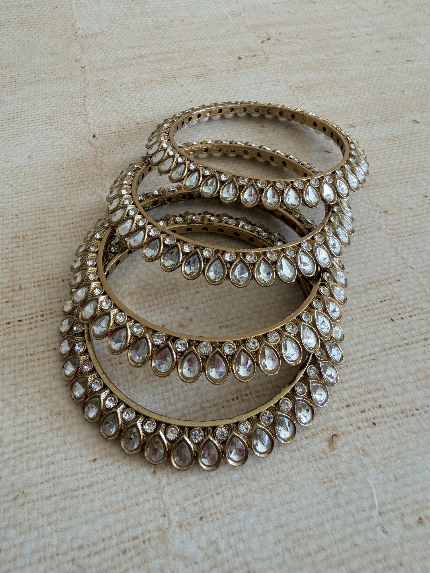 Set of gold hoop earrings with gemstone accents on a textured beige background