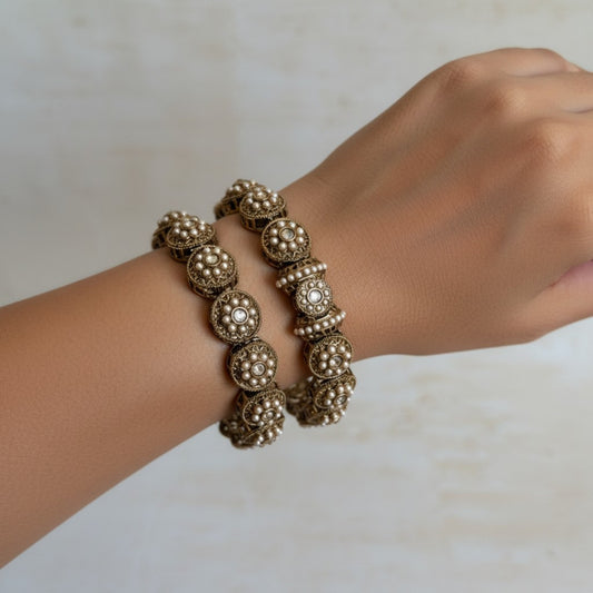 Gold bracelet on a wrist against a neutral background